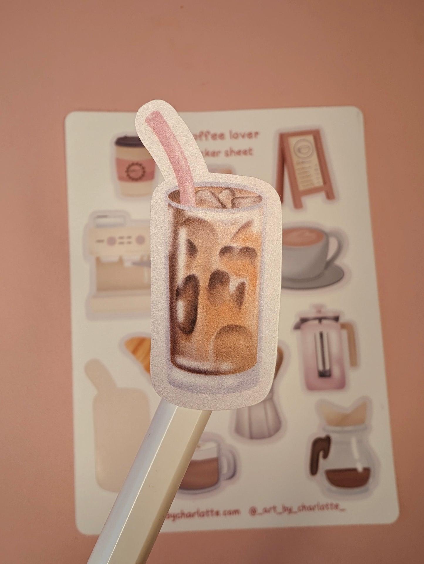 Sticker of a glass of iced coffee with a straw on a pink background