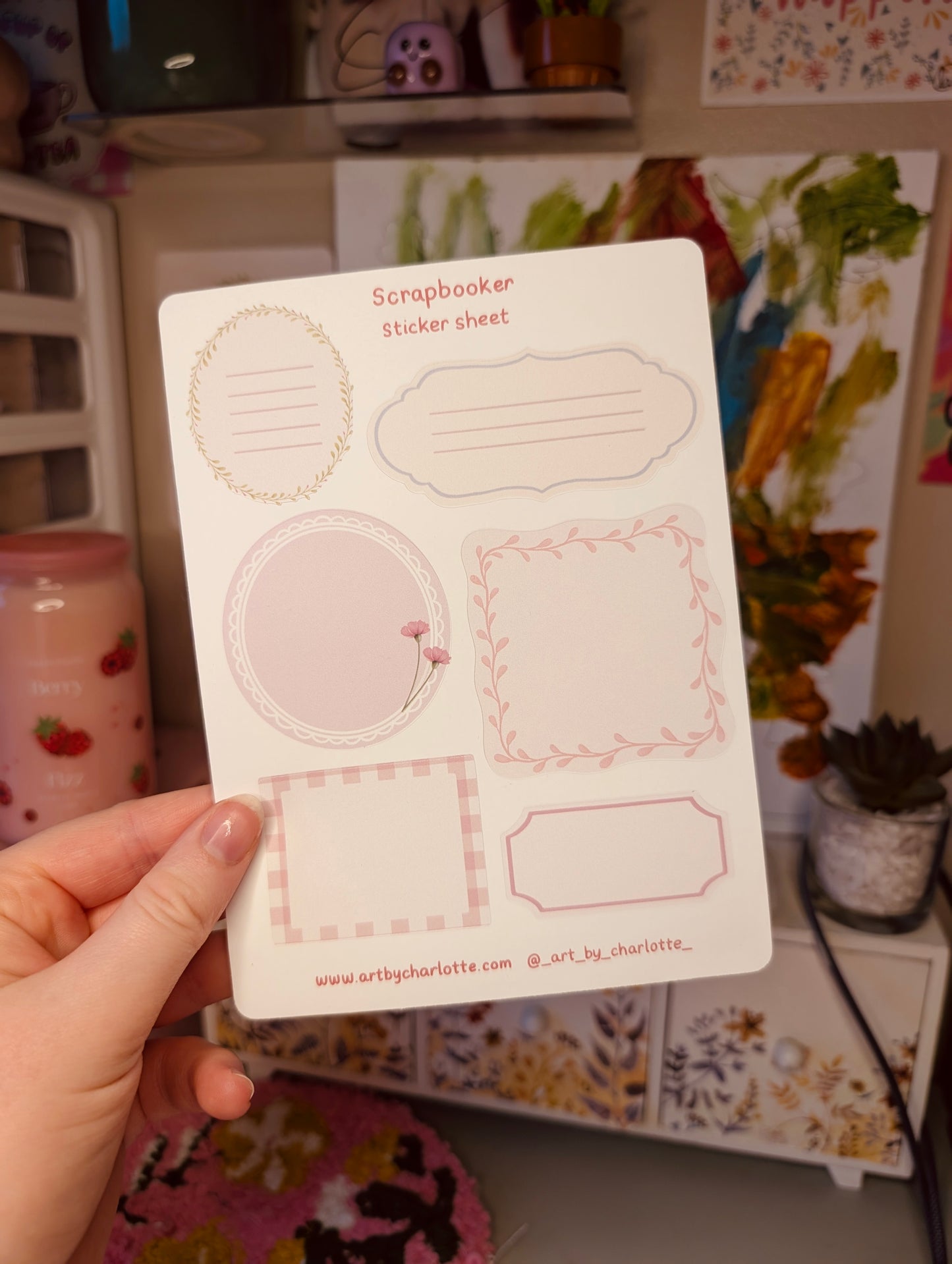 Hand holding a sheet of scrapbooking stickers with decorative elements.