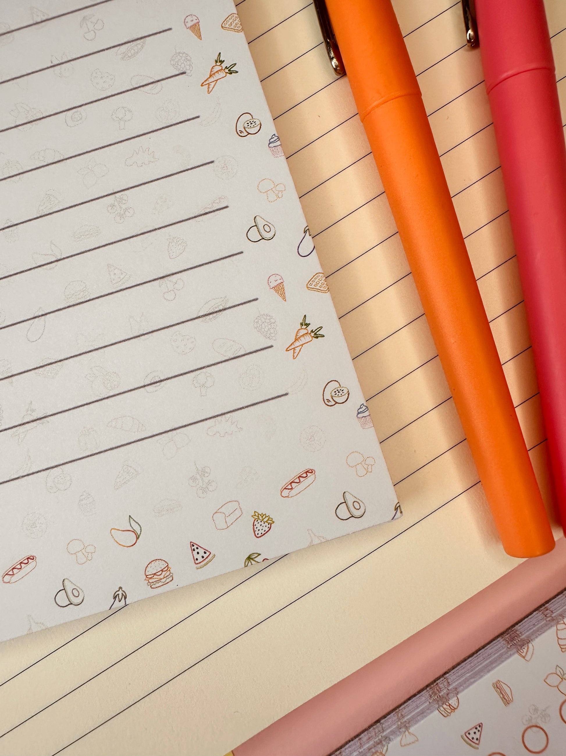 Four colorful pens on a lined notebook with small illustrations.