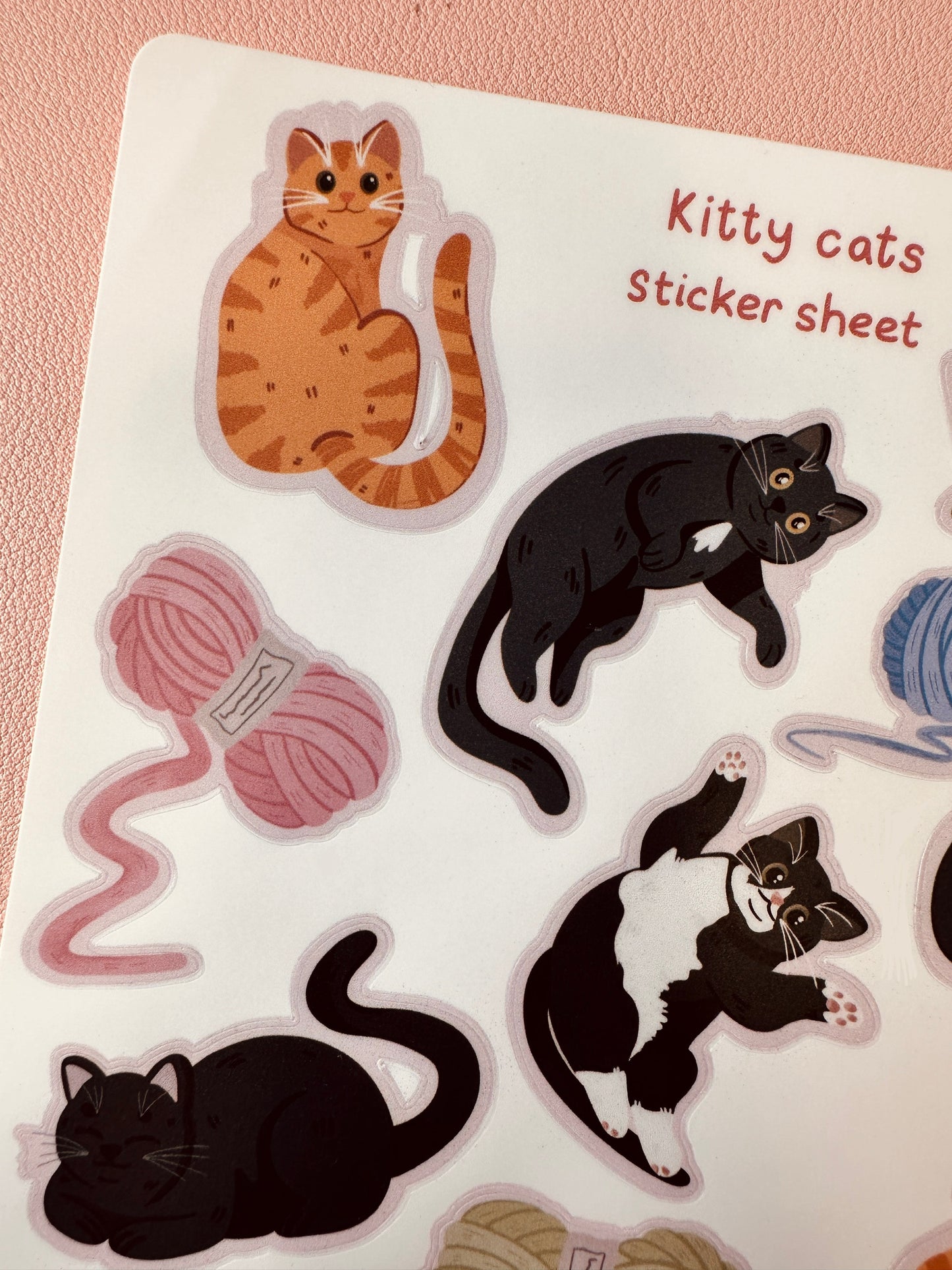 Sticker sheet with cat illustrations and yarn on a pink background